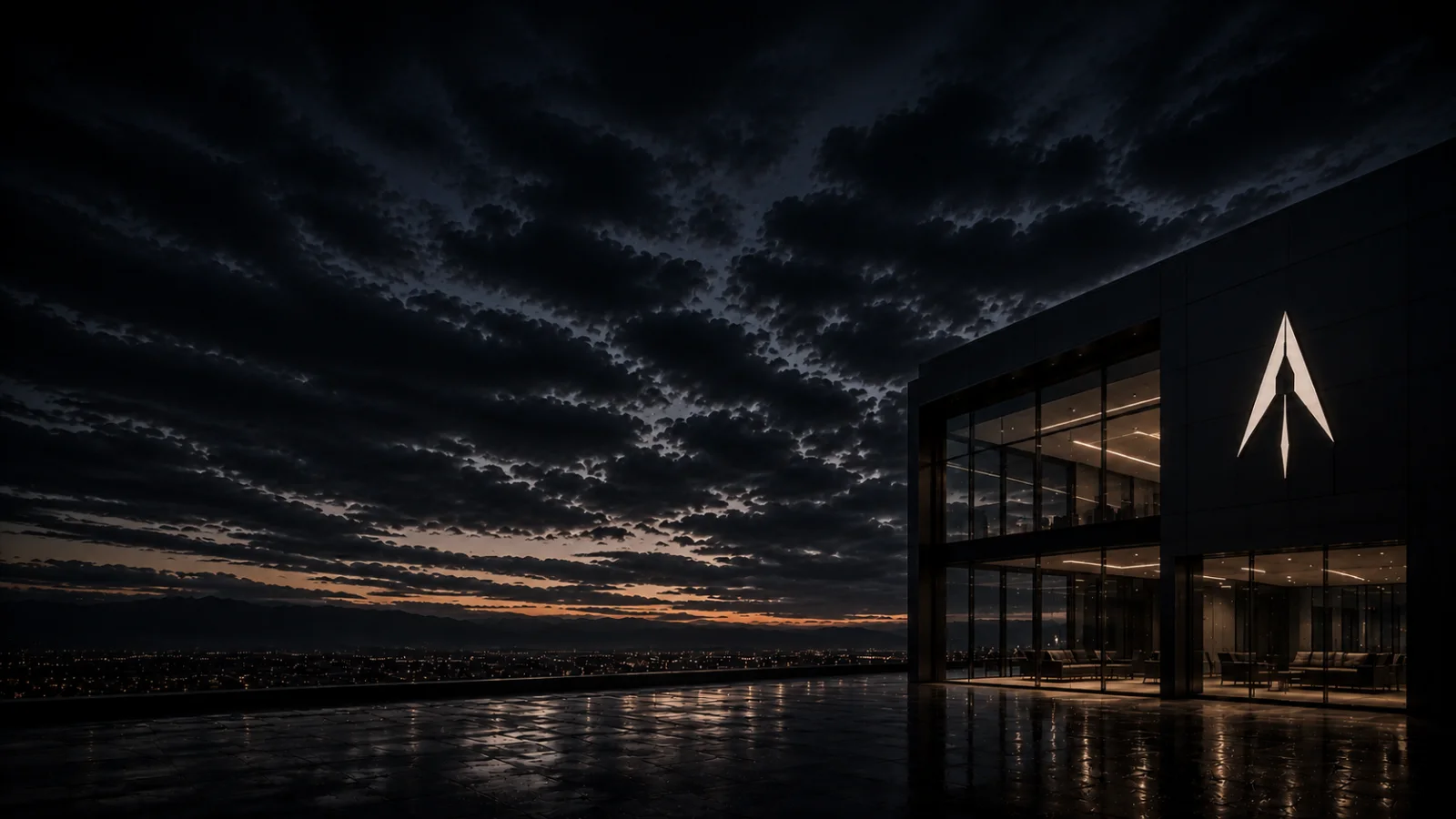 Aero Realty office building at dusk, the illuminated Aero mark on its dark glass facade above a wet stone plaza and distant city lights